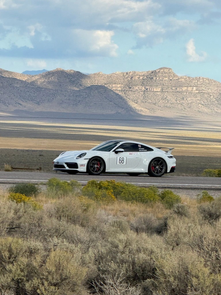 Modified white Porsche 911 S racing on a Nevada highway at golden hour